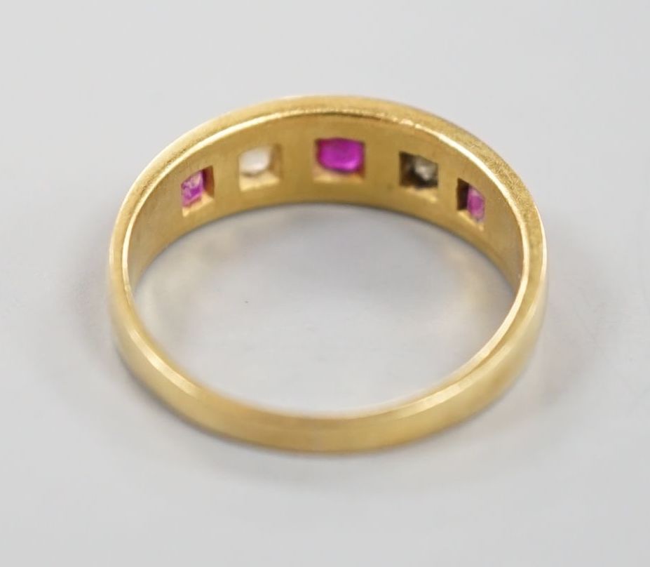 An early 20th century yellow metal and gypsy set three ruby and two stone diamond ring, size P, gross 4.3 grams.